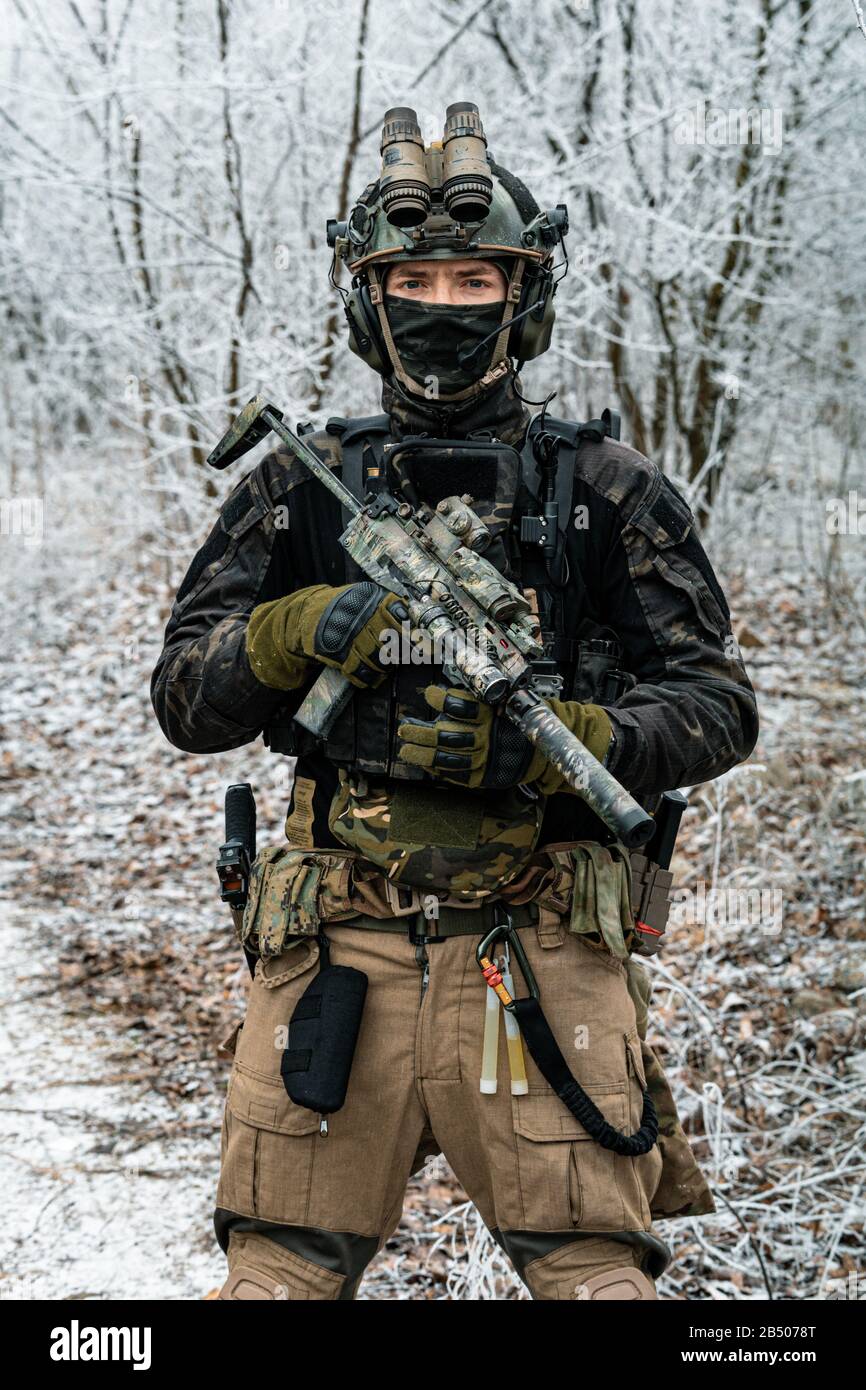 Airsoft man in black camouflage uniform and short machinegun with optical  sight. Soldier in the winter forest. Vertical photo front view Stock Photo  - Alamy