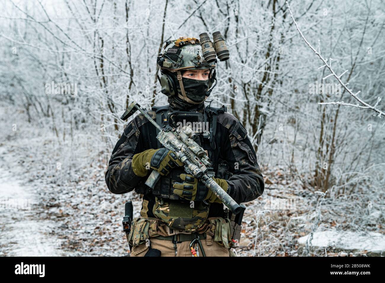 Airsoft man in black camouflage uniform and short machinegun with optical  sight. Soldier in the winter forest. Horizontal photo side view Stock Photo  - Alamy