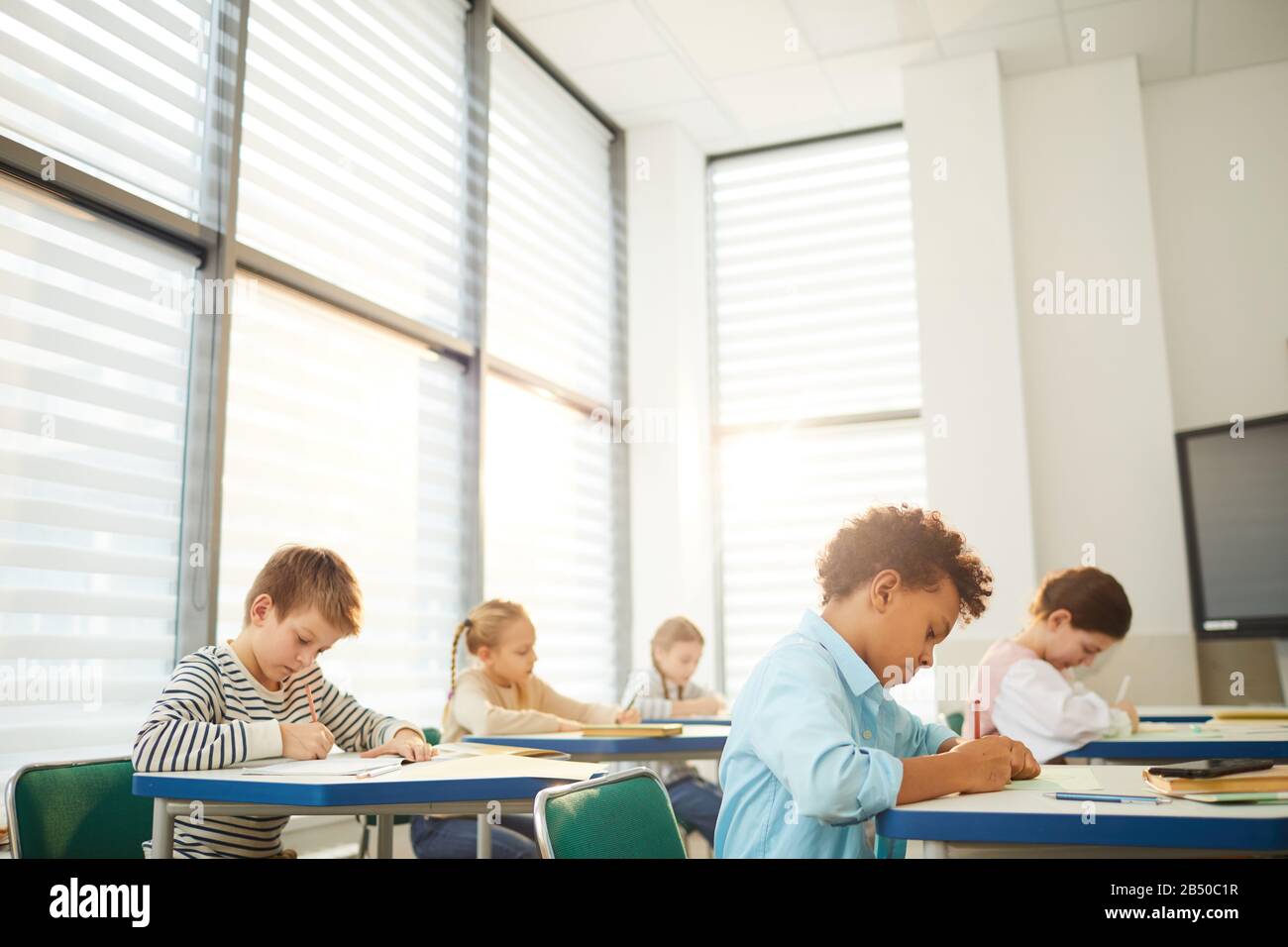 Horizontal shot of young middle school students sitting at desks in