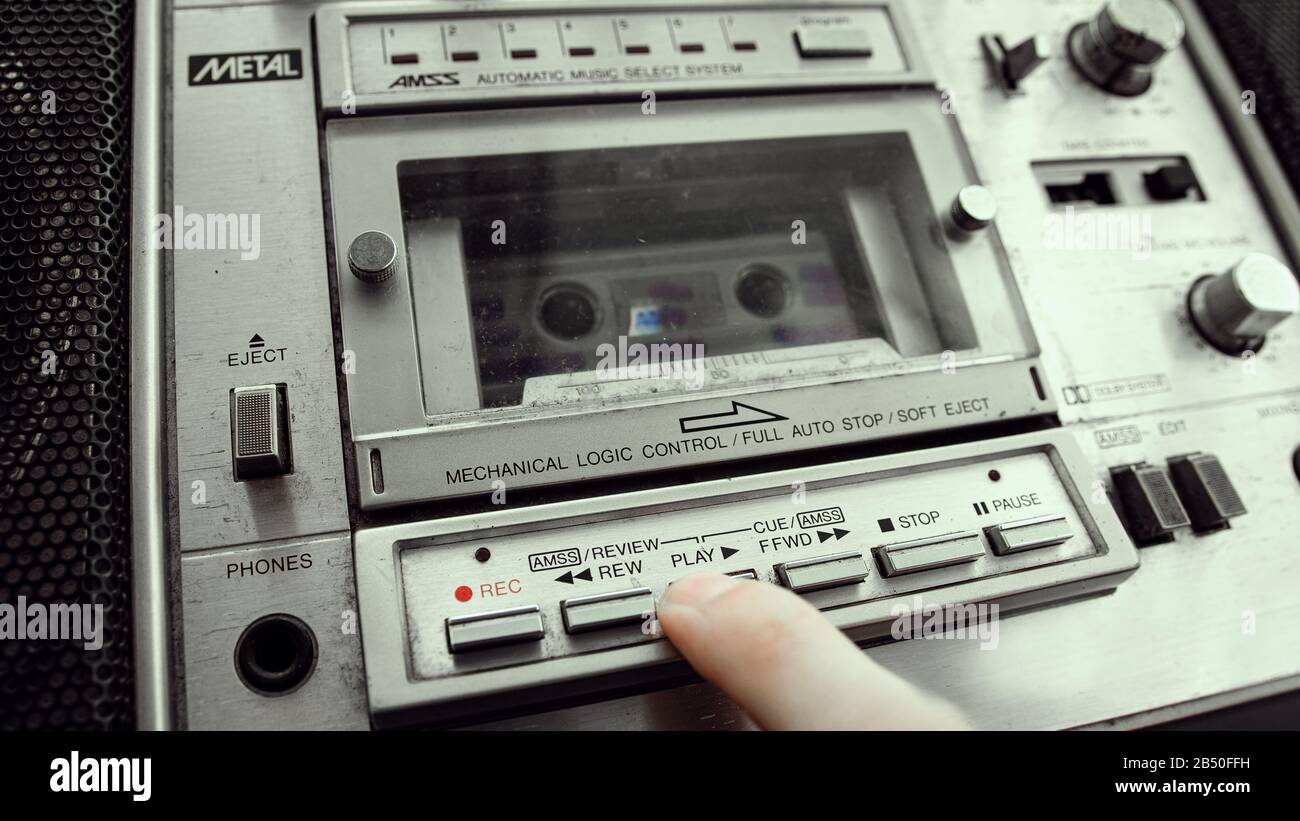 The old cassette player inserts a cassette into the boombox and presses the play button. Retro cassette player concept. Stock Photo