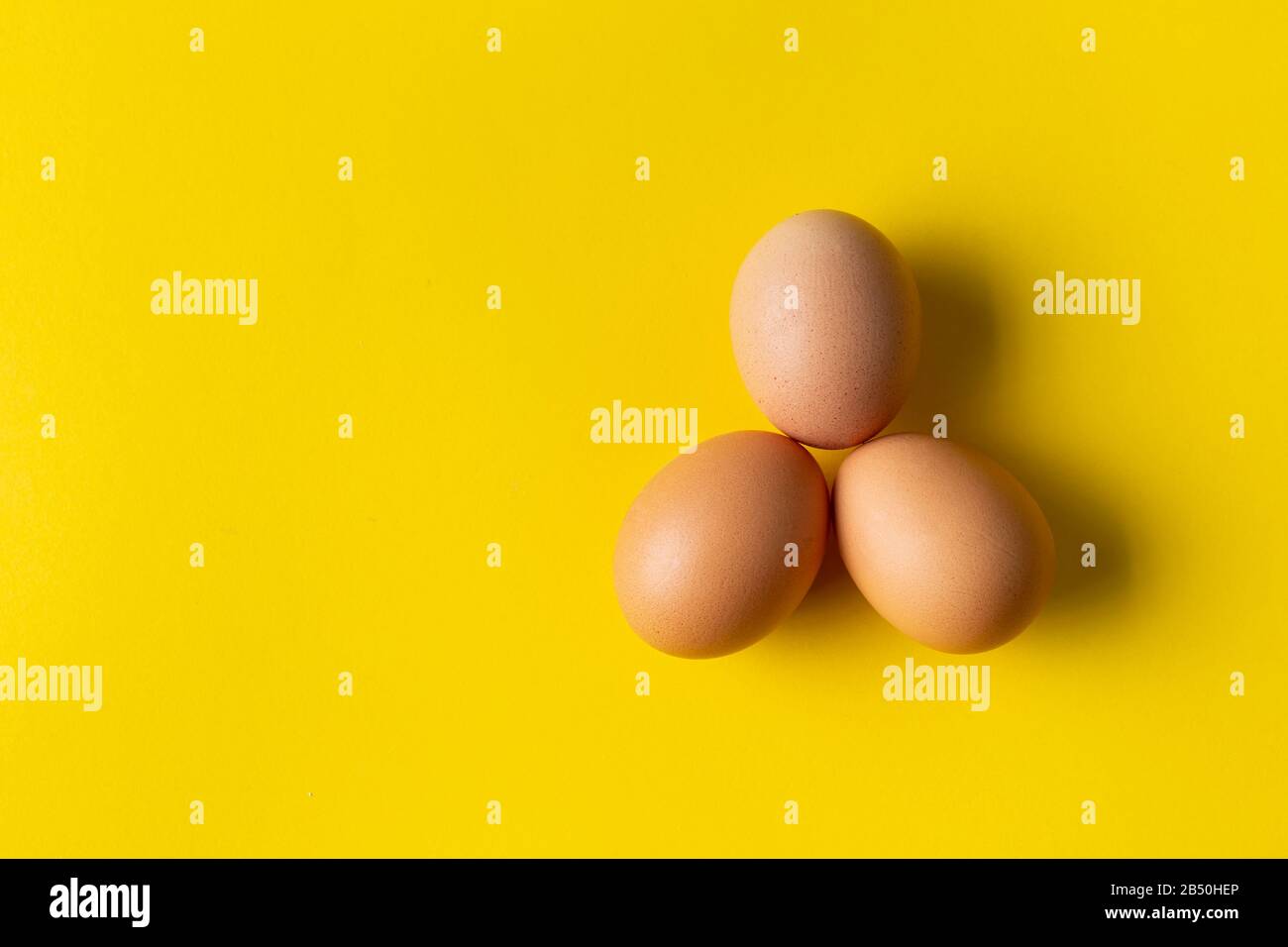 Three eggs on yellow background. View from above. Stock Photo