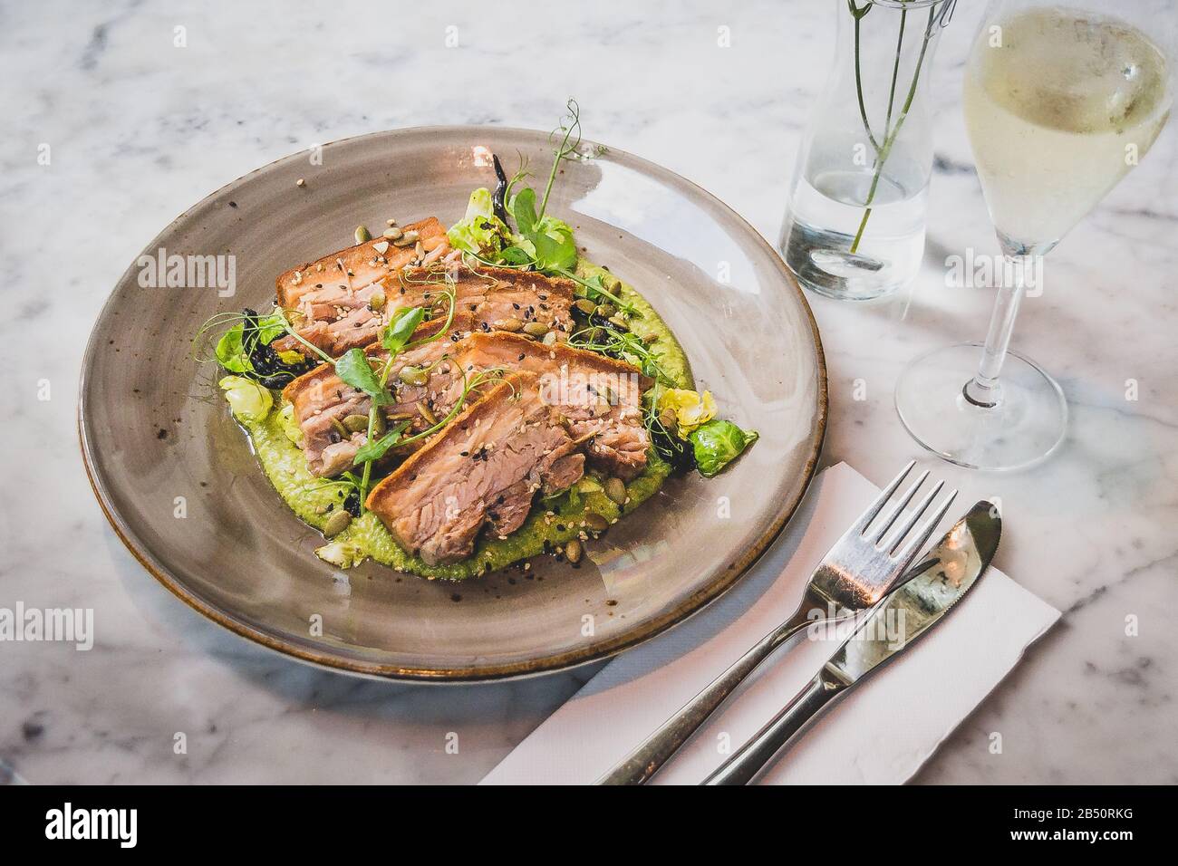 Pork Belly In Pipian Verde 14 hour slow cooked pork belly with crunchy skin, pumpkin seeds and green tomatillos salsa. Stock Photo