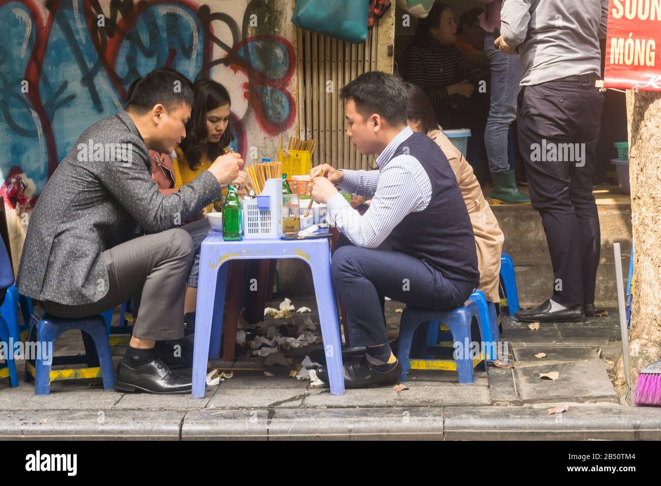 Hanoi street food People having lunch on plastic stools in the Old