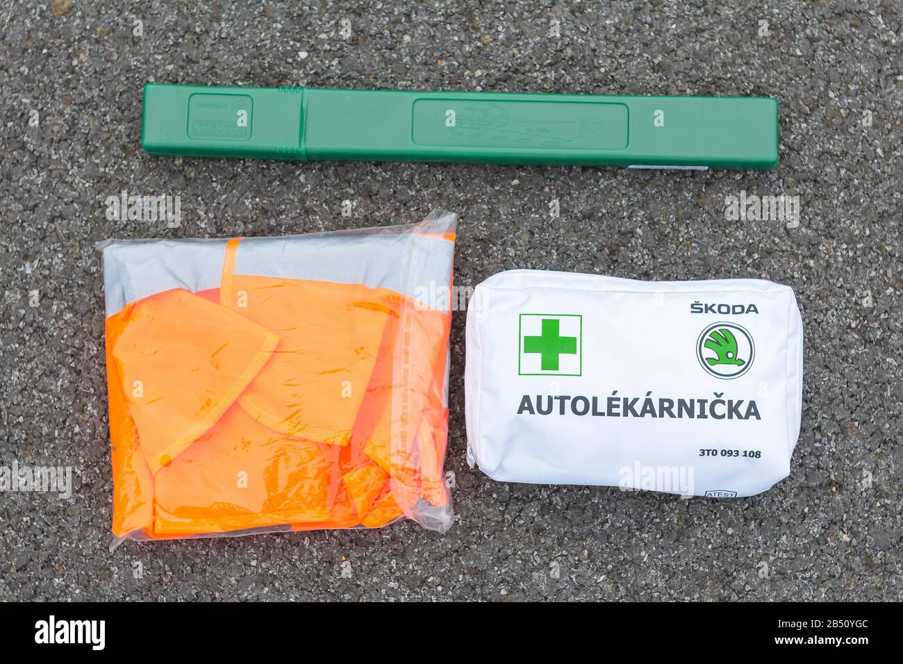 First aid, safety orange vest and green road sign in the car from Skoda Auto on a asphalt road. Emergency tool kit for the first help after car Stock Photo