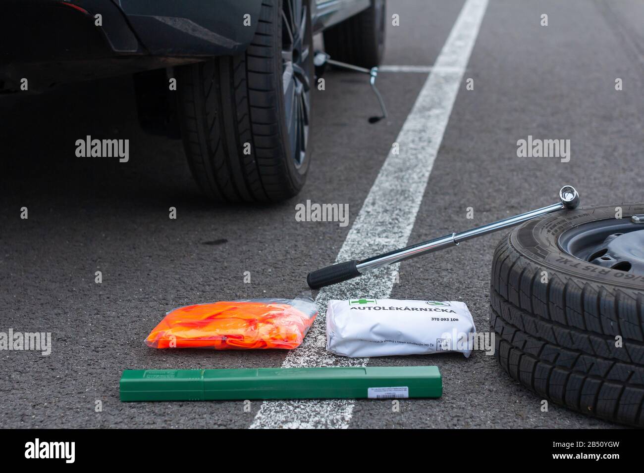 First aid, safety orange vest and green road sign on a asphalt road on the background of a broken car. Emergency tool kit for the first help after car Stock Photo
