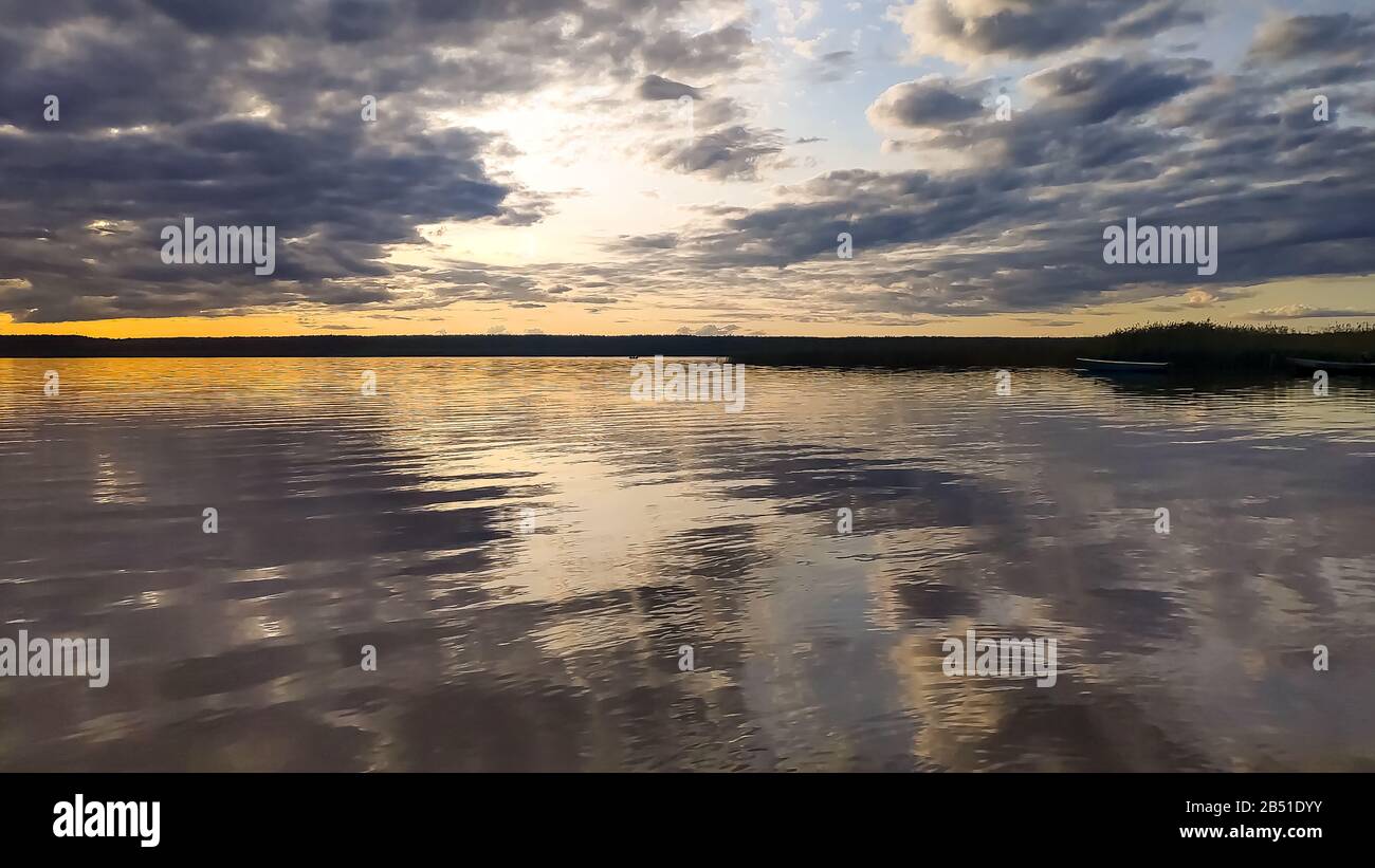 Sunset over the forest lake. View from the boat, image in the orange ...