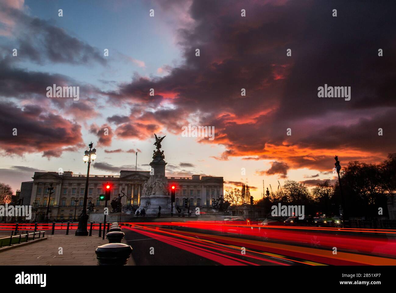 Car brake lights trail under a dramatic sunset at Buckingham Palace, London Stock Photo