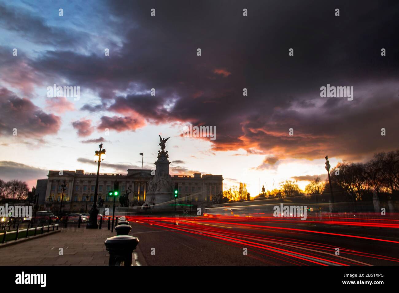Car brake lights trail under a dramatic sunset at Buckingham Palace, London Stock Photo