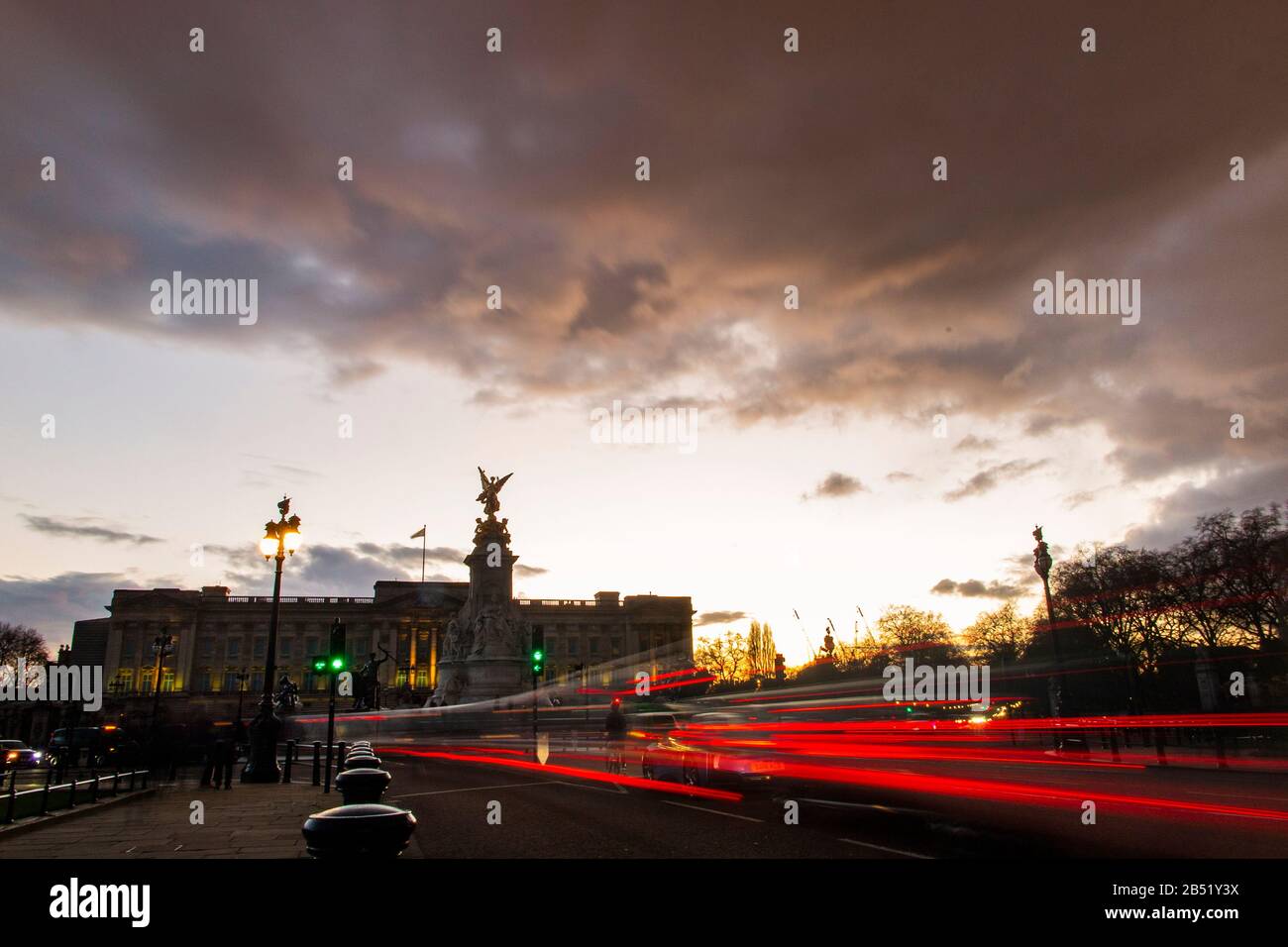 Car brake lights trail under a dramatic sunset at Buckingham Palace, London Stock Photo