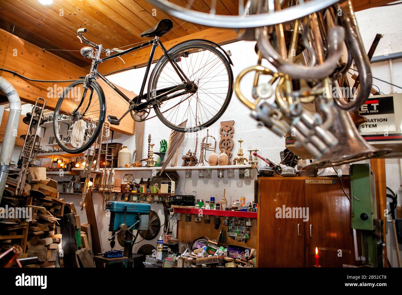 old bicycle hanging from ceiling in brick-a-brack shop with bits and pieces of tools and junk Stock Photo
