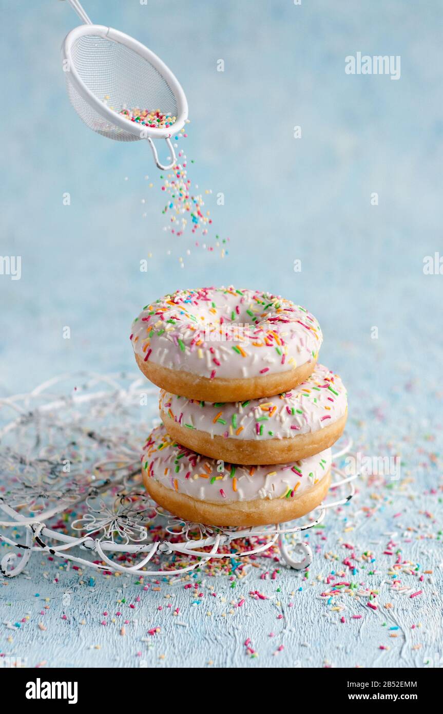 three donuts on a blue background with colorful sugar sprinkles Stock ...