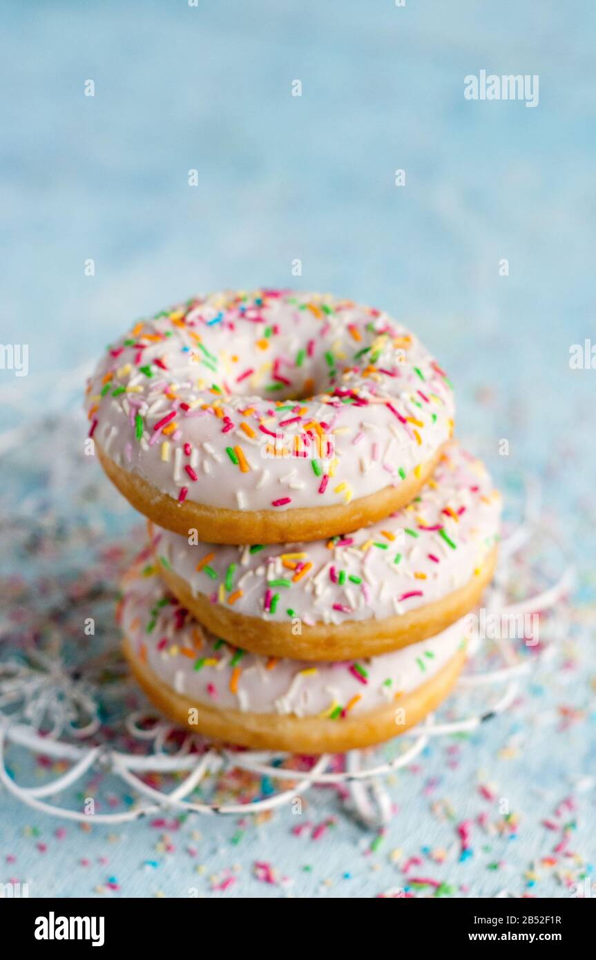 three donuts on a blue background with colorful sugar sprinkles Stock ...