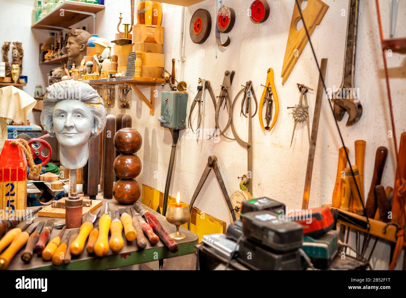 plaster bust in artist workshop with variety of tools and chisels hanging on wall Stock Photo