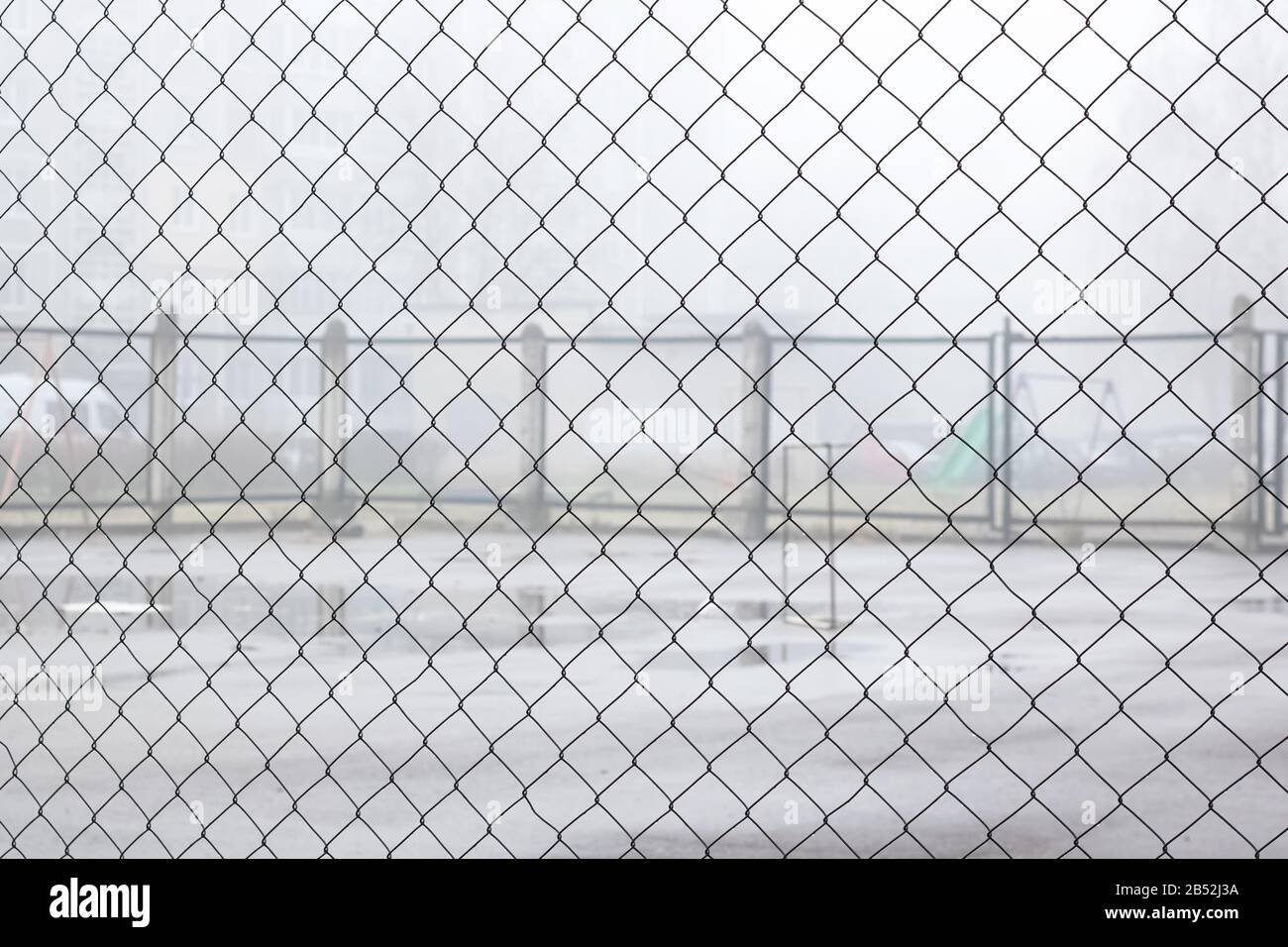 Fence net against backdrop of playground for games in fog Stock Photo