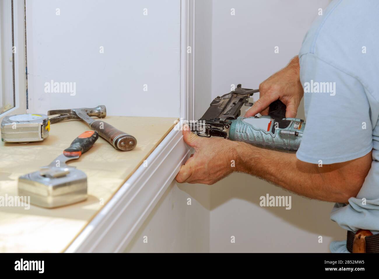 Worker installing trim around a window molding installed moldings