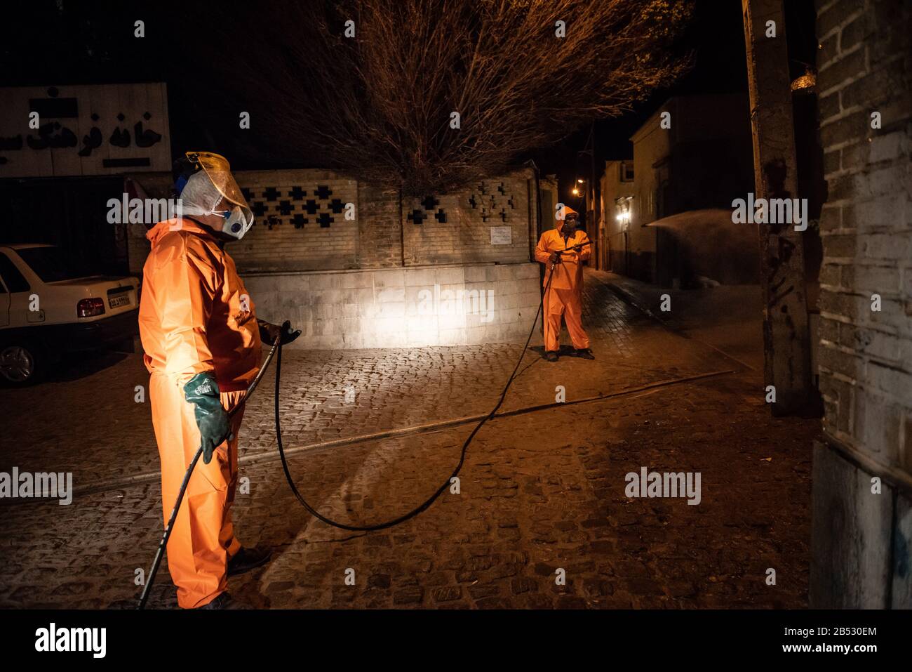 Iranian health ministry staff, the provincial fire department and municipal staffs are disinfecting public places to prevent Coronavirus(COVID19) at late night using machinery and mobile pumps at Historical urban context and alleys of Shiraz city, Fars province, Iran. Schools, Sport cpmplex, Concerts and all social gatherings have been canceled in Iran. Stock Photo