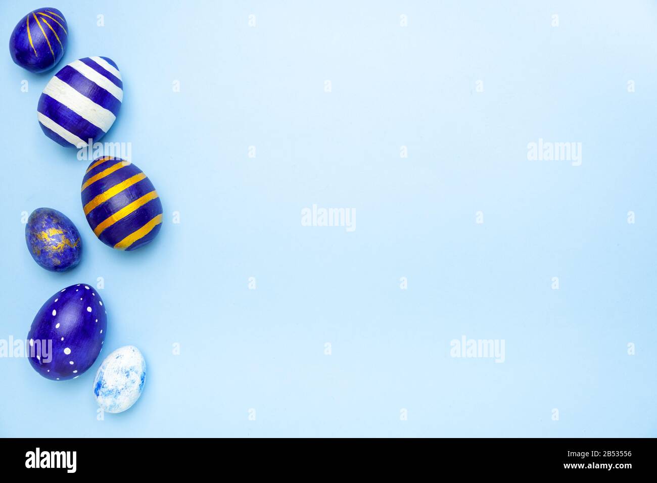 Happy Easter. Frame for text made of easter eggs trendy colored classic blue, white and golden on blue. Minimal style, top view, flatlay, copy space. Stock Photo