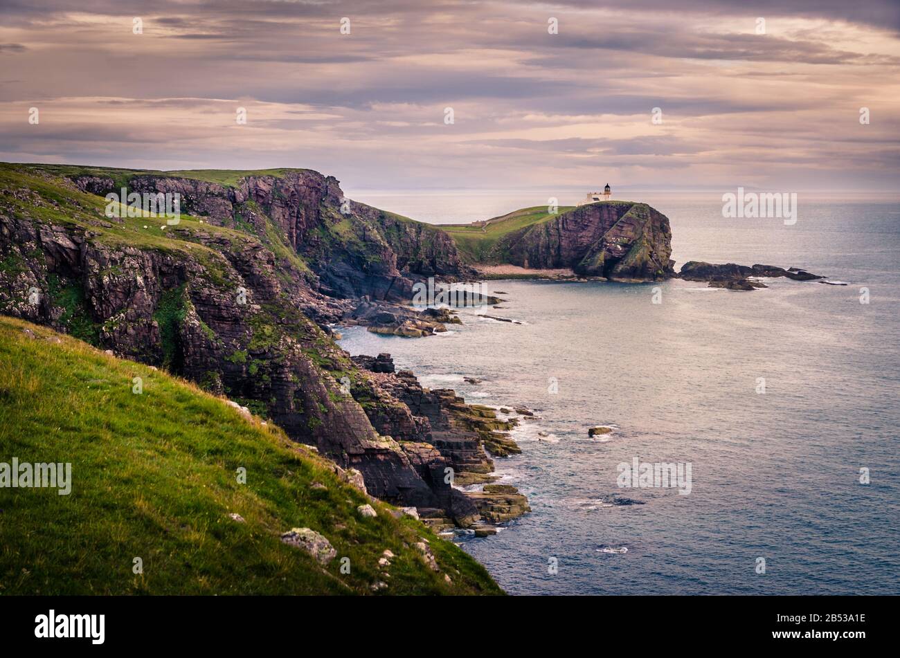 Lighthouse on a sea coastline cliff during sunset, Scotland Stock Photo