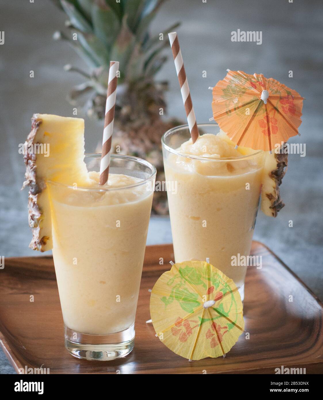 Homemade, frozen rum cocktail with pineapple garnish, straws and paper