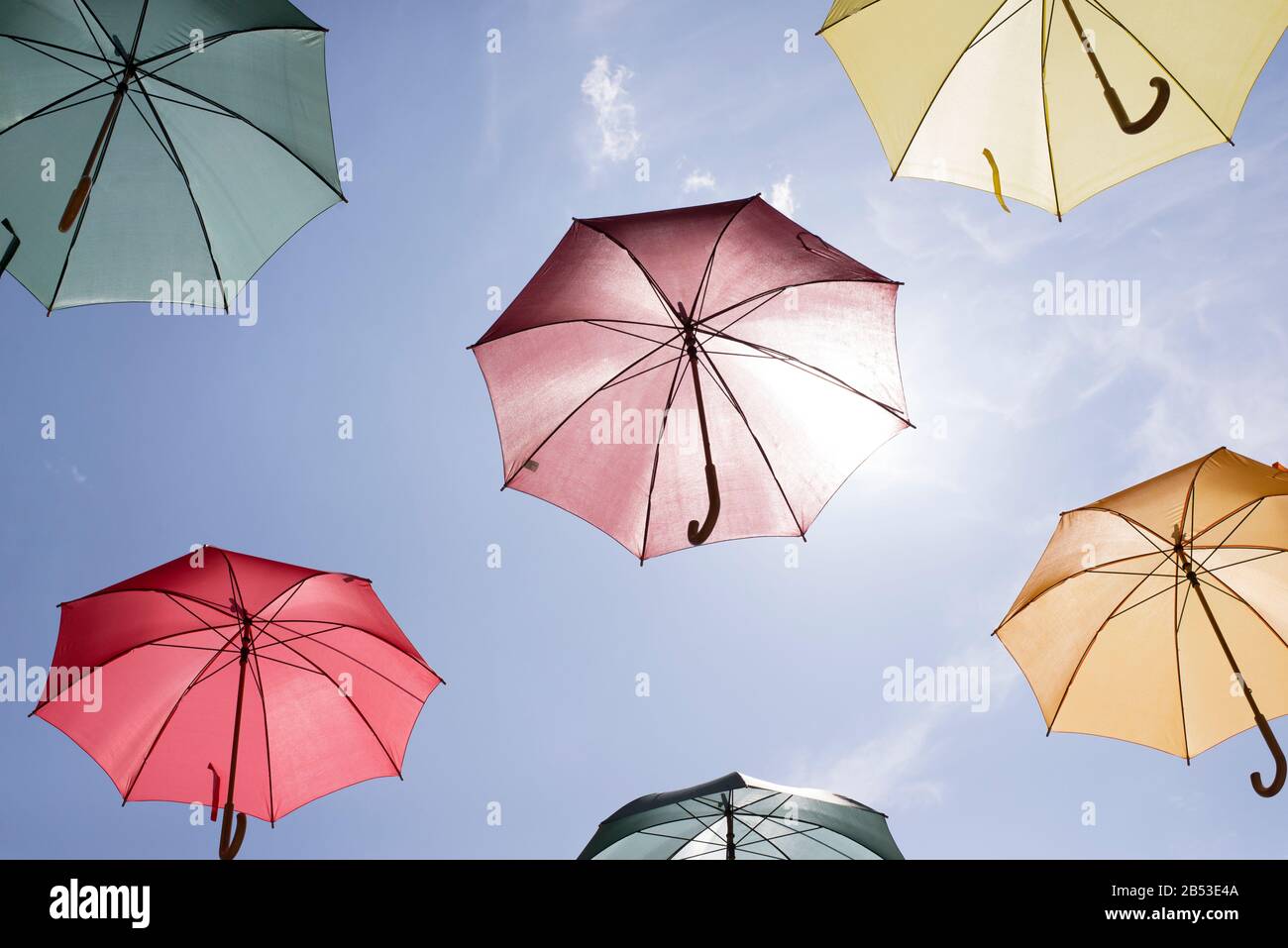 Multicolored umbrellas against a sunny blue sky. Stock Photo