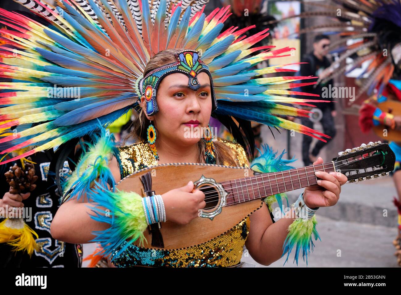 Celebration of the Señor de la Conquista  in elaborate pre-Hispanic costumes and plumed headdresses. Portrait of woman playing instrument. San Miguel Stock Photo