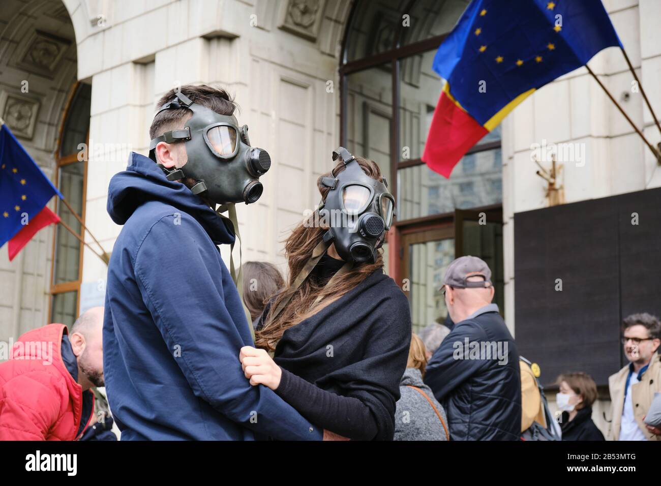 Bucharest, Romania - March 4, 2020: Couple wearing gas masks in protest for extreme air pollution, in front of the Ministry of Environment building, w Stock Photo