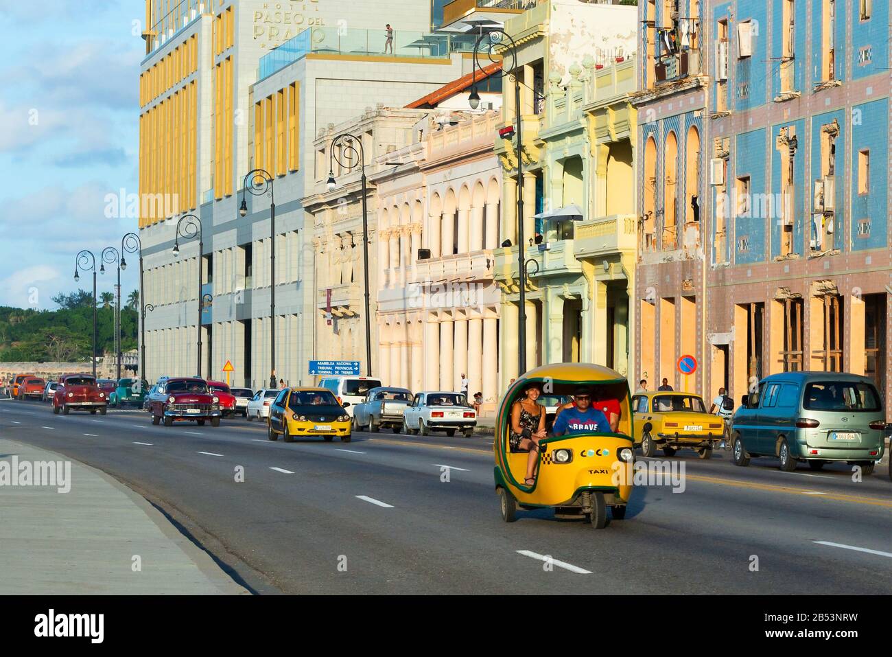 Traffic of vehicles including tuk tuk (coco taxi) in front of colonial style building. View of the promenade called Malecón in Havana, Cuba. Stock Photo