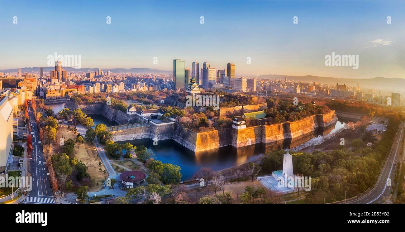 Aerial panorama of Osaka city skyline over historic park with stone walls, water moat and old towers. Stock Photo