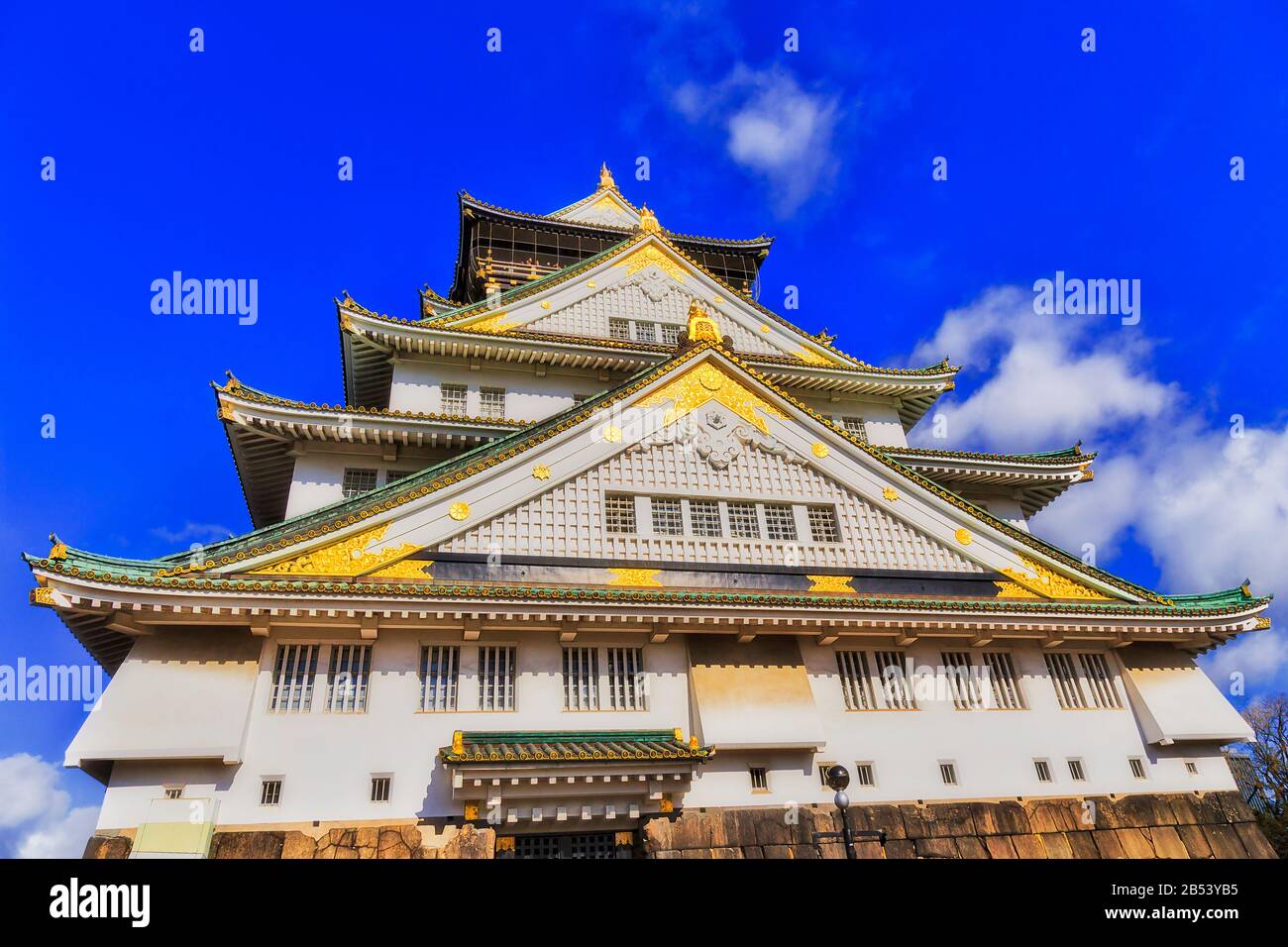 Bright lit facade of spectacular historic castle tower in Osaka city of Japan against blue sky. Stock Photo