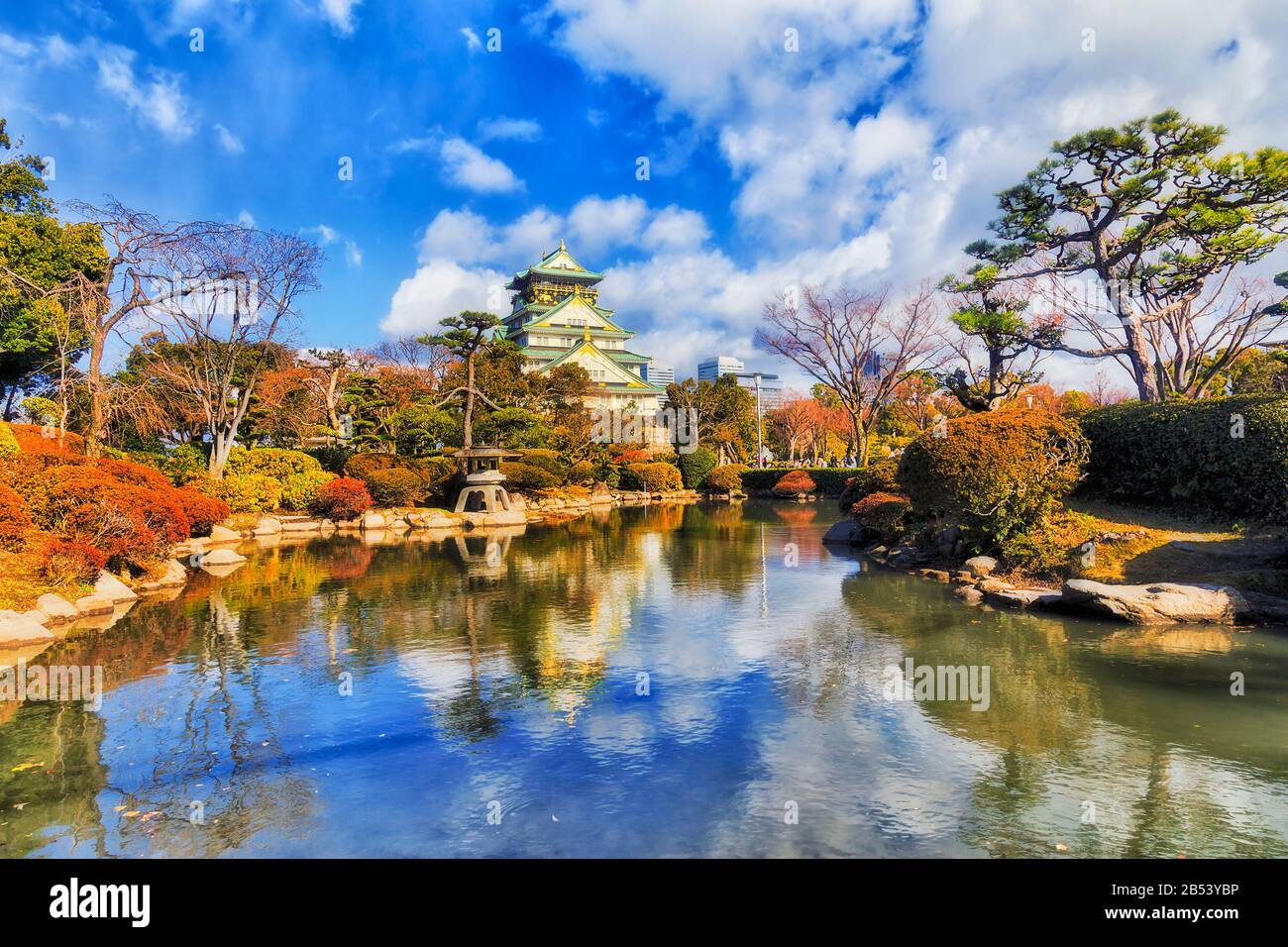 Small pond in traditional japanese garden of Public park in Osaka city on a sunny day with reflection of trees and towers. Stock Photo