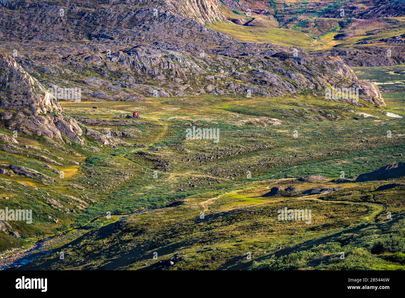 Red hut in distance on the meadows of Arctic Circle Trail, Greenland Stock Photo
