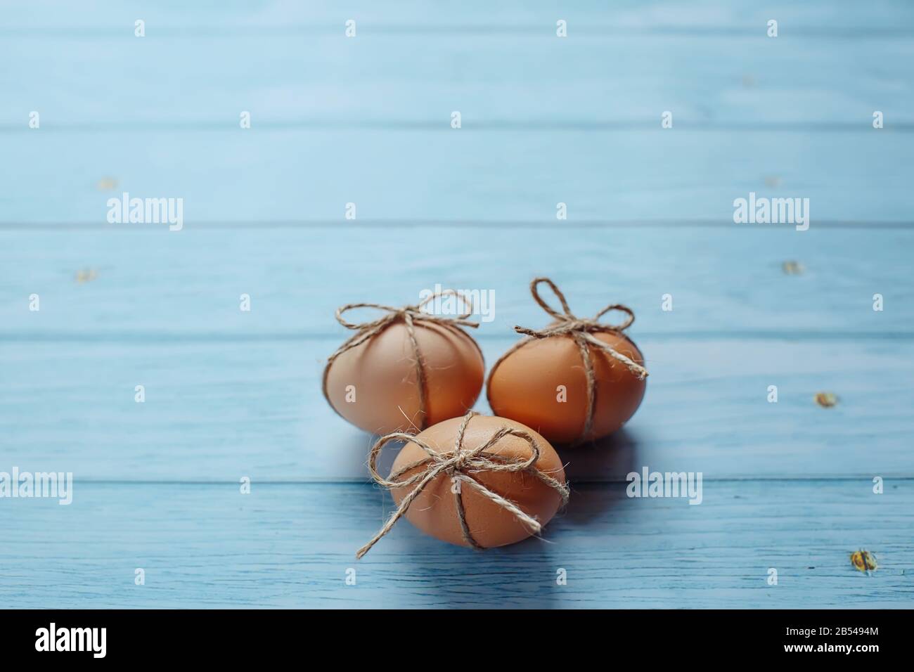 Easter beige eggs decorate with rope on blue wooden background with copyspace Stock Photo