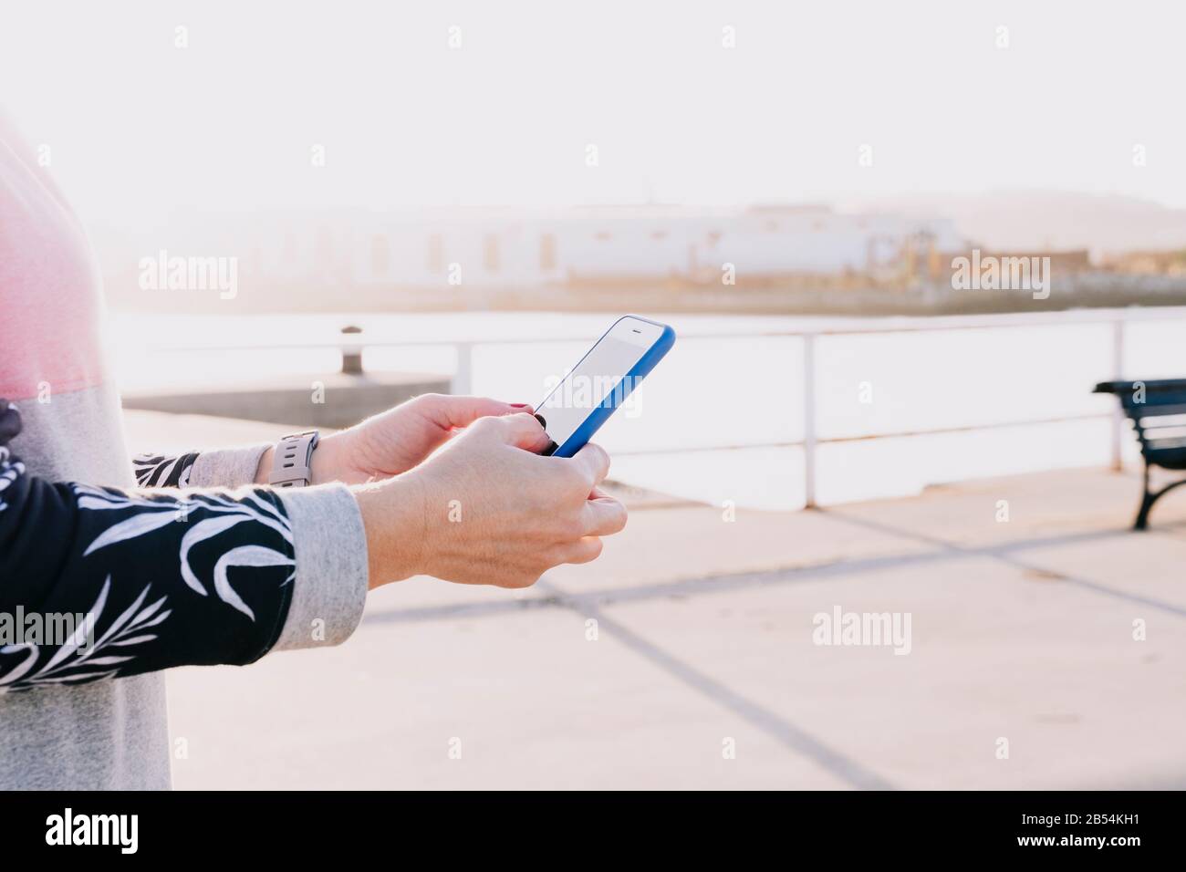 Hands of a woman holding a mobile phone close up on a sunny day Stock Photo