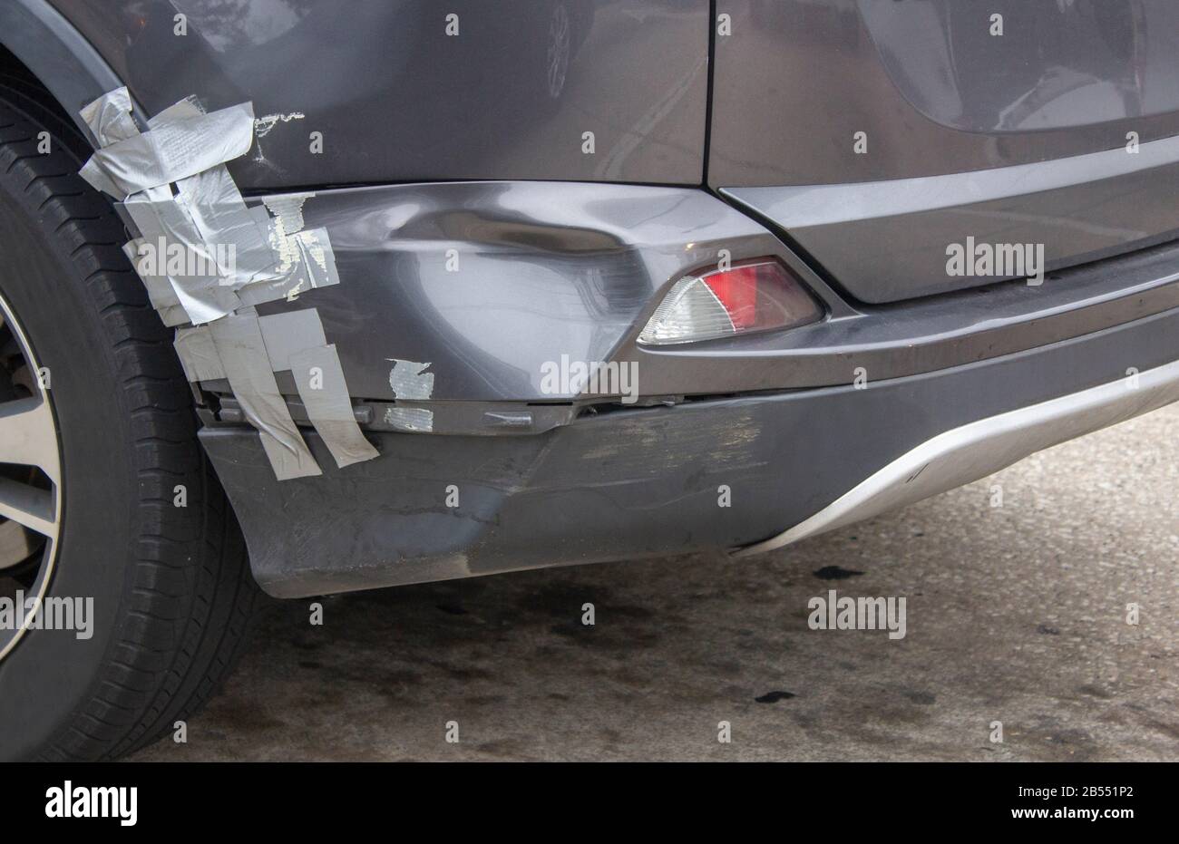 a gray car with a dented rear bumper that is held together with duct tape Stock Photo