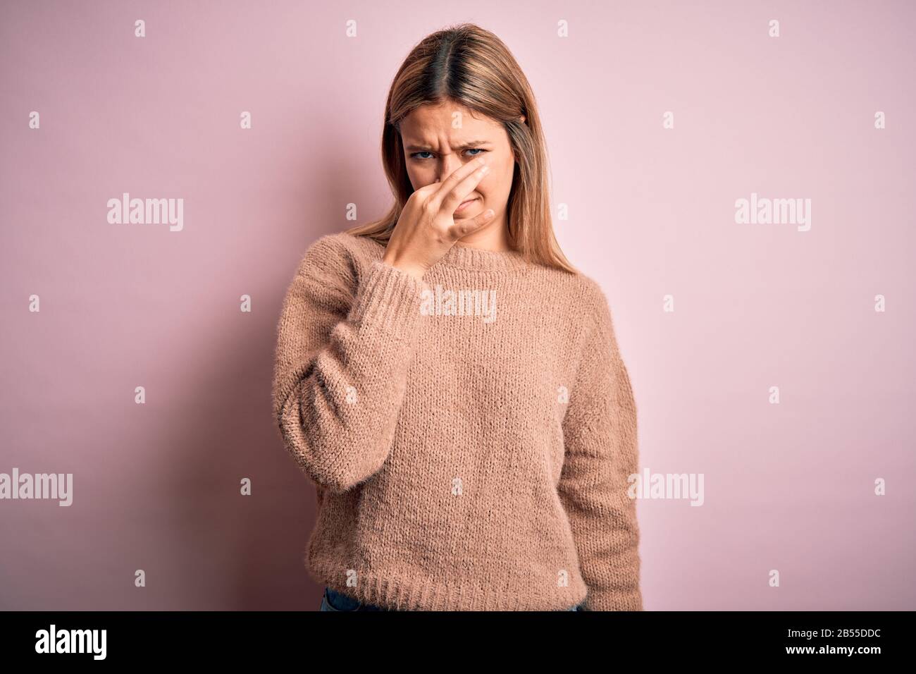Young beautiful blonde woman wearing winter wool sweater over pink