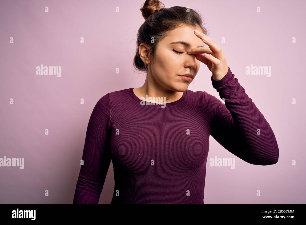 Beautiful young woman wearing casual bun hairstyle over pink isolated background tired rubbing