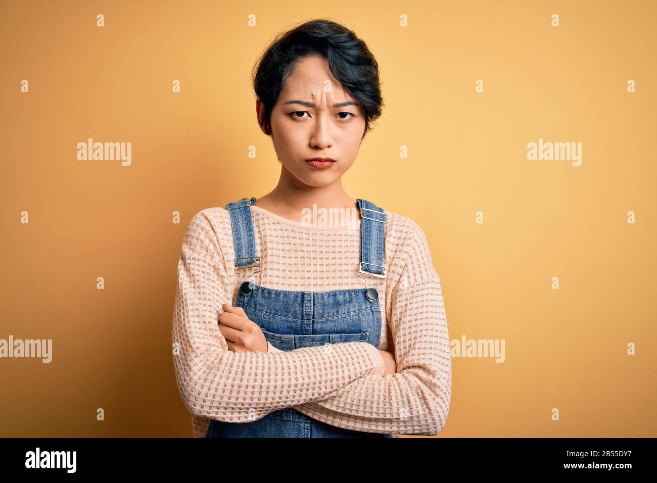 Young beautiful asian girl wearing casual denim overalls over isolated ...