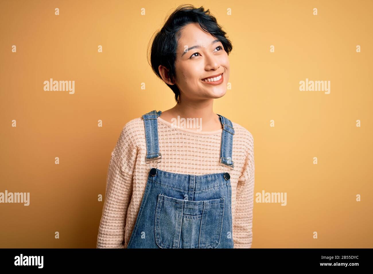 Young beautiful asian girl wearing casual denim overalls over isolated ...