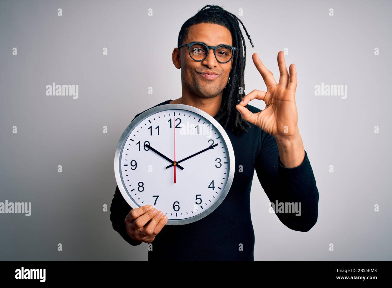 Young african american afro man doing countdown holding bic clock over  white background doing ok sign with fingers, excellent symbol Stock Photo -  Alamy