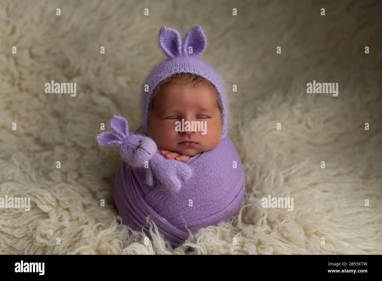 newborn baby girl pose cocoon with ears on the head and a bunnies toy on a  white background. first photo session of a newborn Stock Photo - Alamy