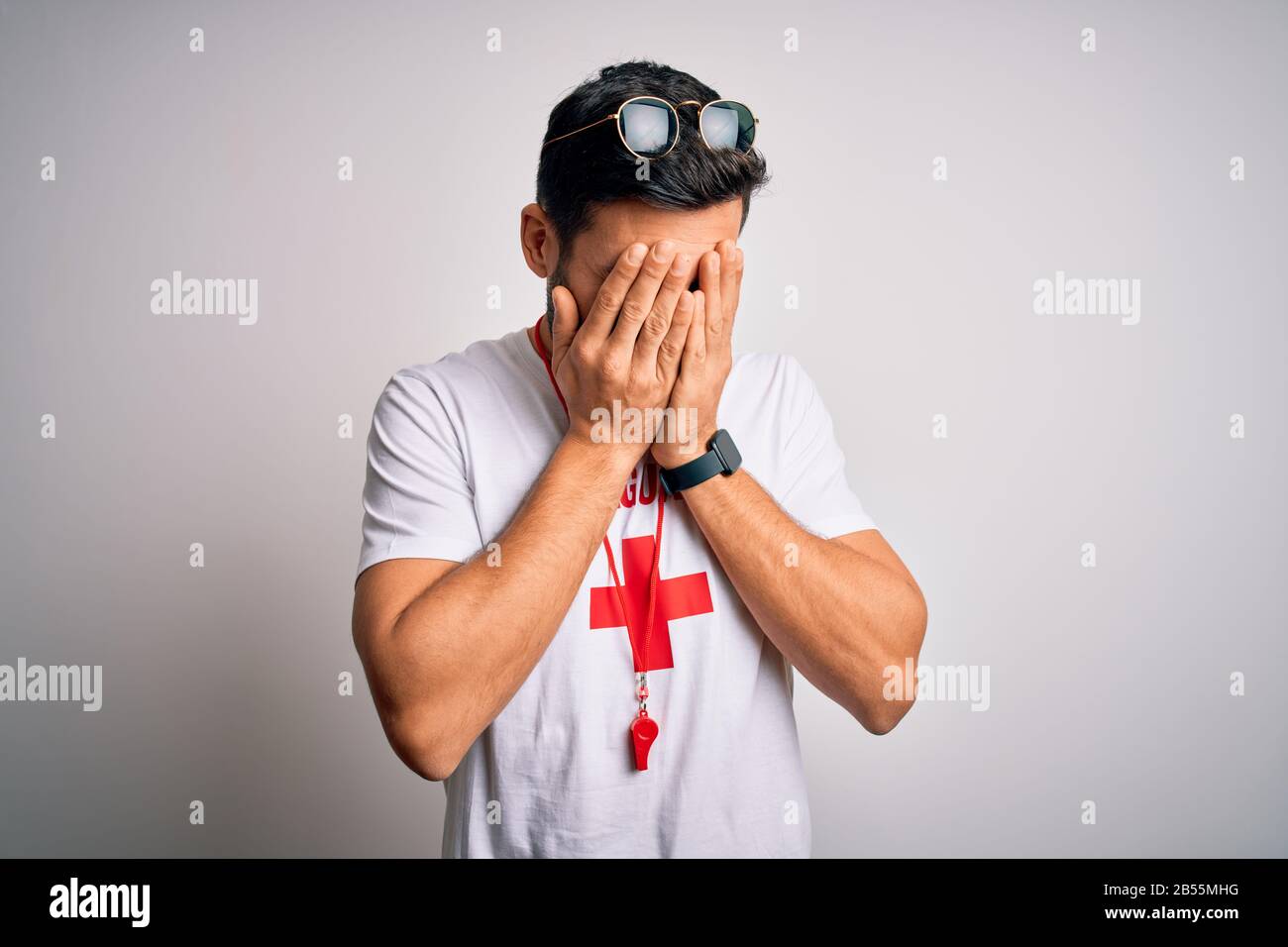 Young handsome lifeguard man with beard wearing t-shirt with red cross ...