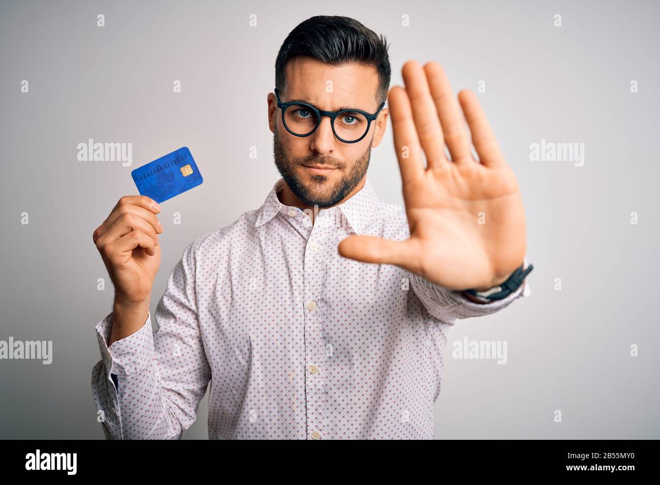 Young business man holding credit card over isolated background with ...