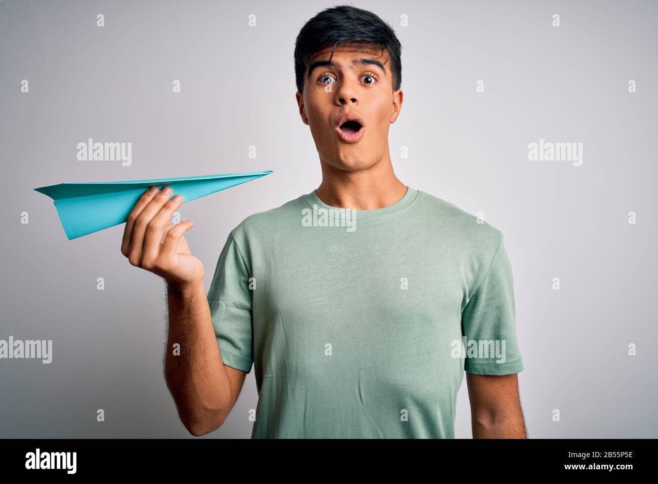 Afraid Paper Young handsome man holding paper airplane over isolated white ...