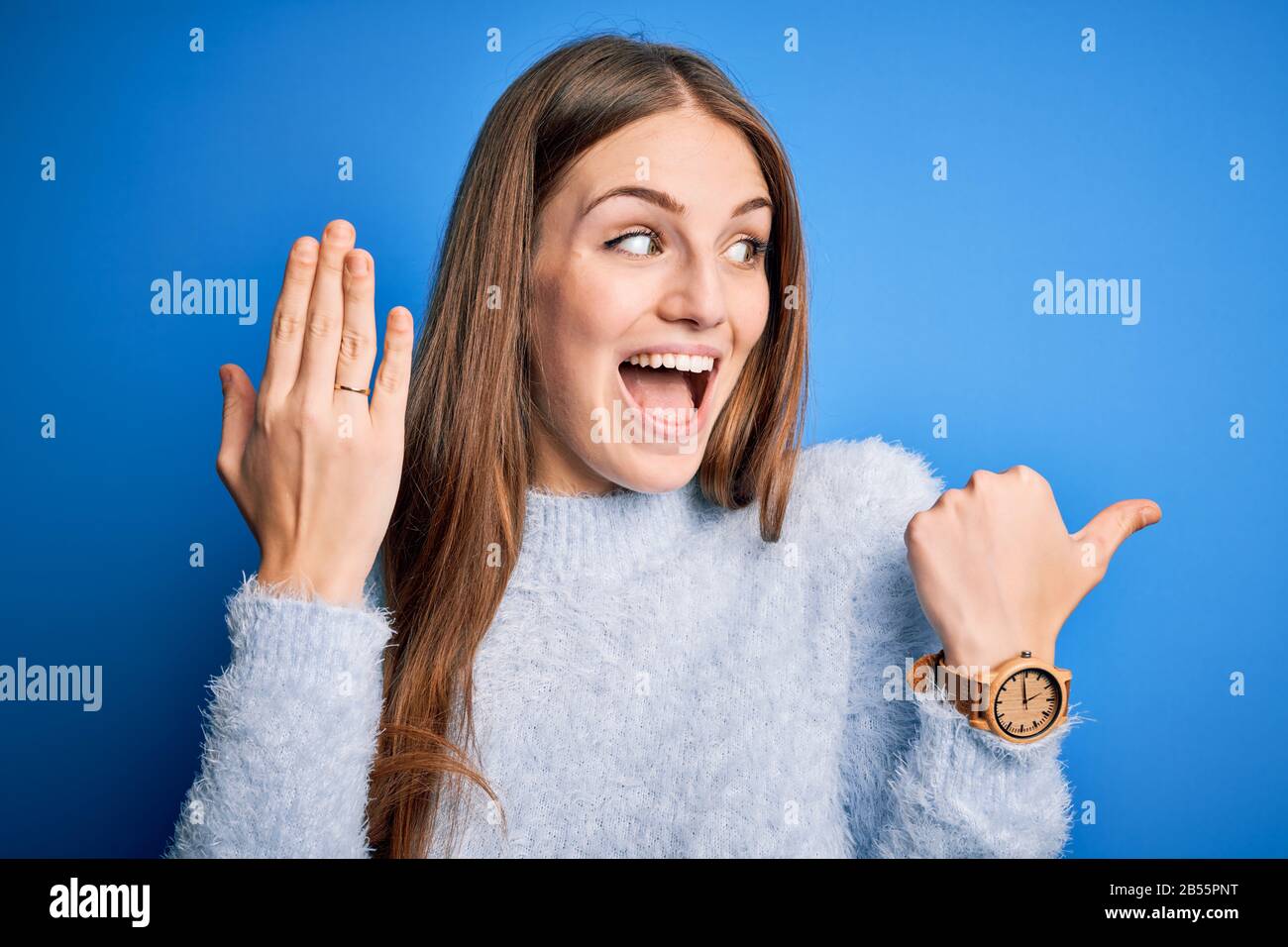 Young beautiful redhead woman wearing wedding ring on finger over blue