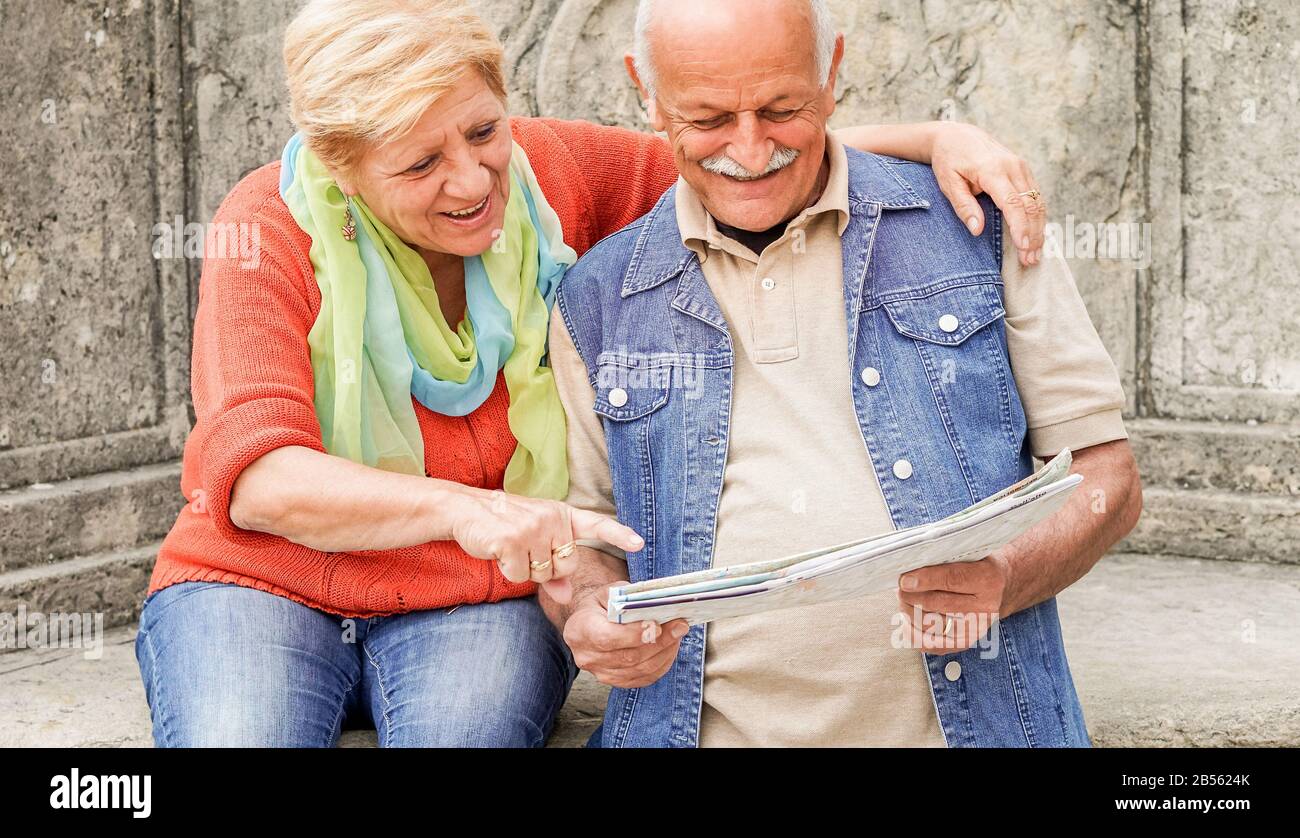 Senior couple reading tourist map inside italian castle outdoor - Mature Husband and wife having fun in romantic vacation- Love and joyful elderly lif Stock Photo