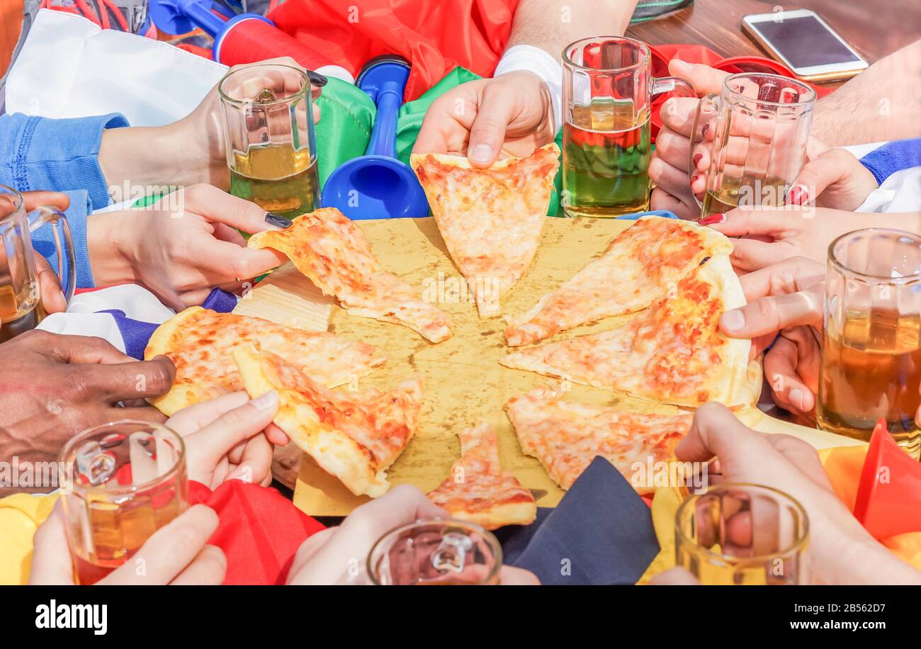 Multi ethnic hands of football friend supporter sharing pizza