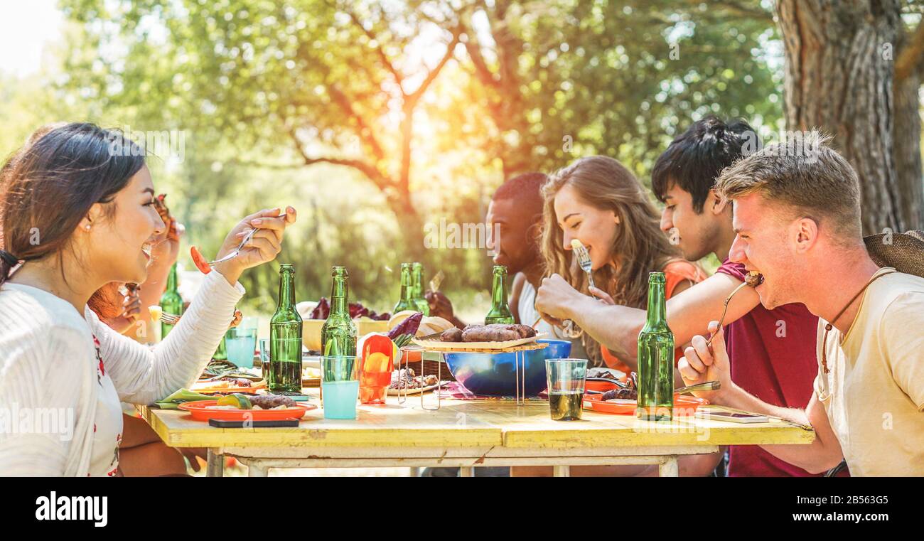 Happy friends eating dinner at barbecue party outdoor in nature