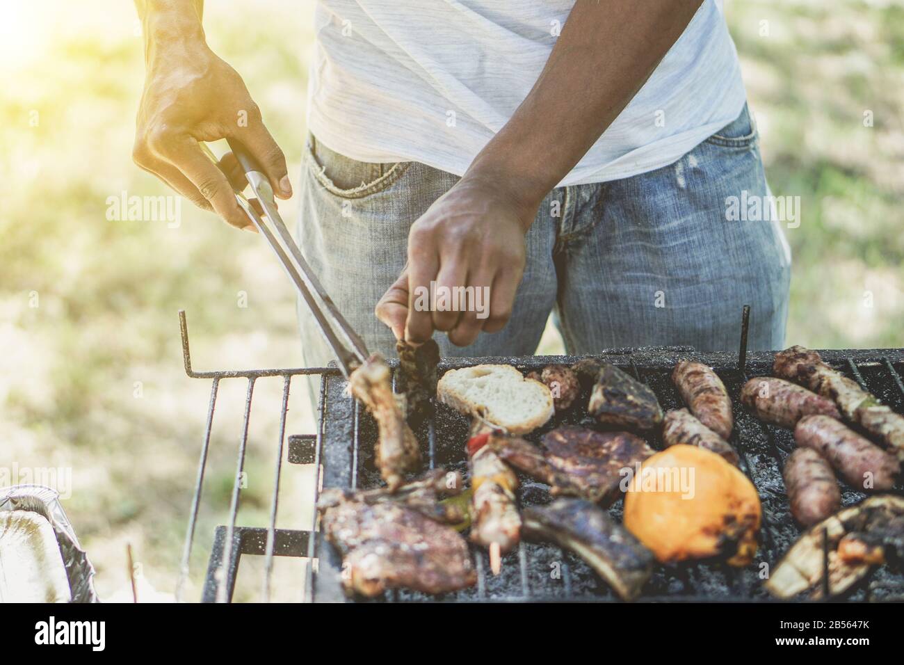 Afro american man cooking meat on barbecue - Chef putting some sausages on  grill in park outdoor - Concept of eating outdoor during summer time - Vint  Stock Photo - Alamy