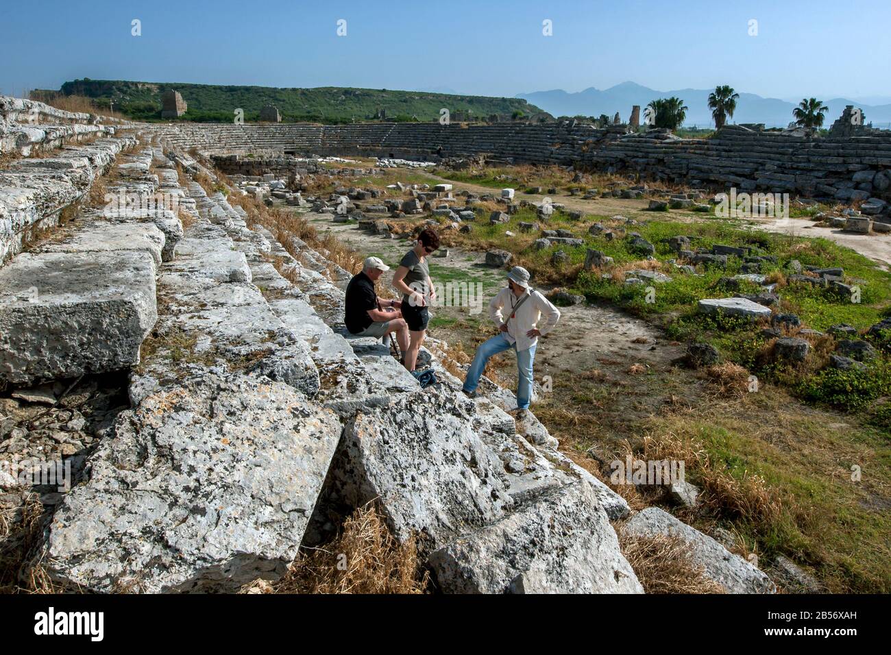 A Turkish tour guide explains to tourists the history of the stone ruins of the ancient stadium of Perge in Turkey. Stock Photo