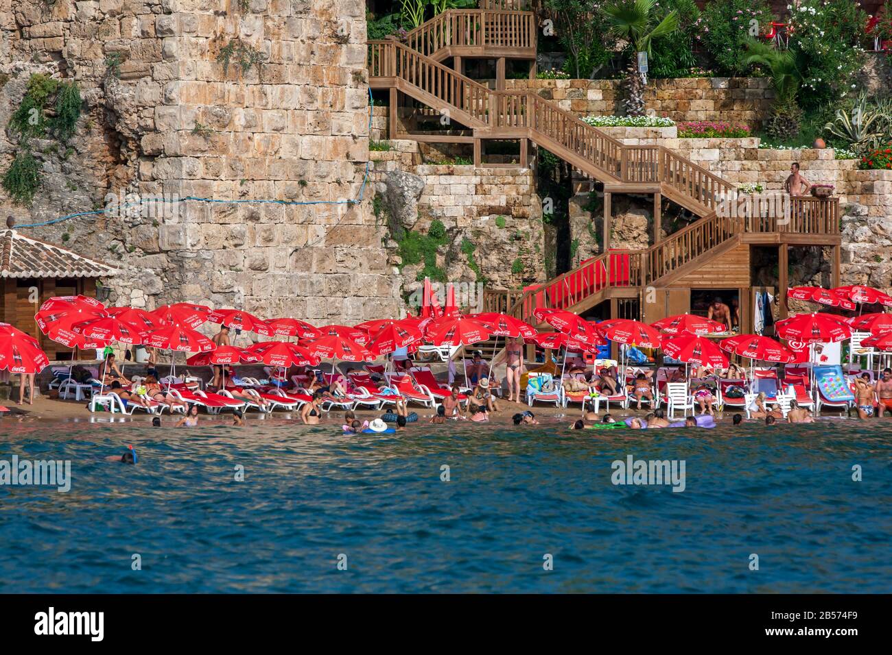 People enjoy bathing at Mermerli Plaji adjacent to the ancient Roman Harbour walls at Kaleici on Antalya  Bay in Turkey on a hot summers day. Stock Photo
